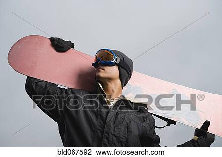 Stock Image - Mixed race teenager standing with snowboard. Fotosearch