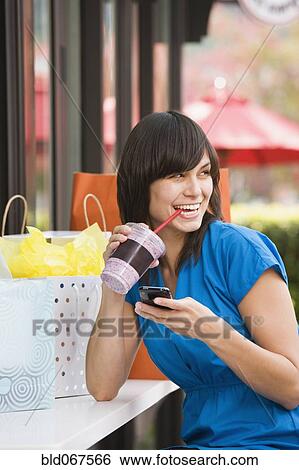 Stock Photograph - Mixed race woman text messaging on cell phone. Fotosearch
