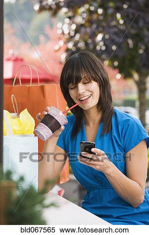 Stock Photography - Mixed race woman text messaging on cell phone. Fotosearch