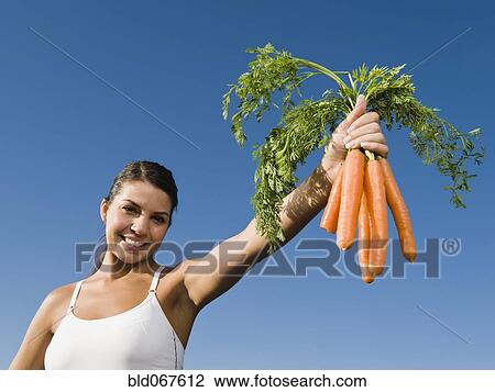 Stock Image - Native American woman holding bunch of carrots. Fotosearch