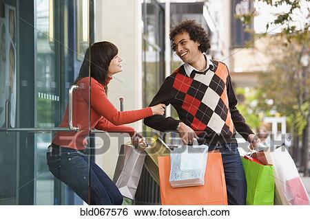 Stock Photograph - Woman trying to pull boyfriend back into store. Fotosearch