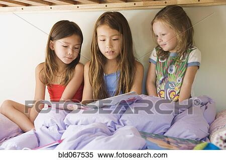 Stock Photography - Young girls reading story on bunk bed. Fotosearch