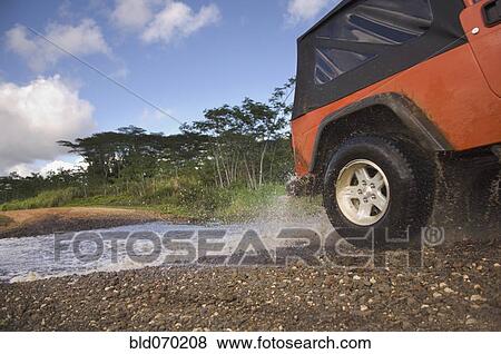 Stock Photo - 4x4 driving through water on remote road . Fotosearch
