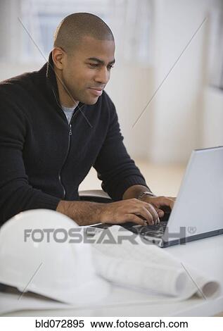 Stock Photography - African American architect using laptop. Fotosearch