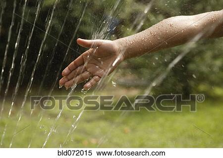 Stock Photography - African American boy's hand in sprinkler. Fotosearch