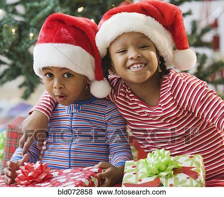 Stock Photo - African American brother and sister holding Christmas gifts. Fotosearch