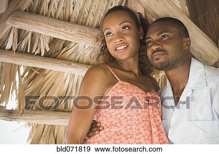 Stock Photo - African American couple hugging in grass hut. Fotosearch