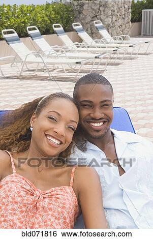 Stock Photograph - African American couple laying on lounge chair. Fotosearch