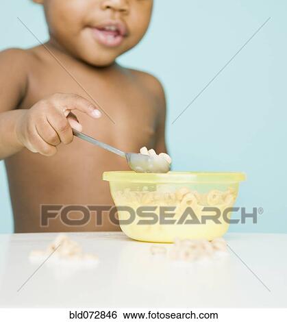 Stock Photograph - African American girl eating cereal with spoon. Fotosearch