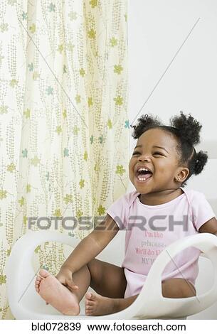 Stock Photo - African American girl laughing in chair. Fotosearch