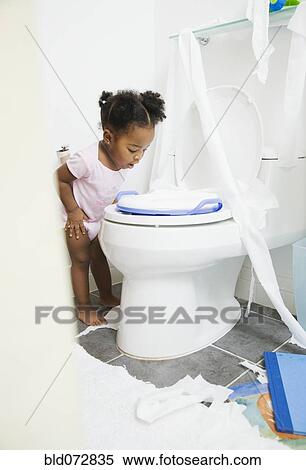 Stock Photography - African American girl looking into toilet. Fotosearch