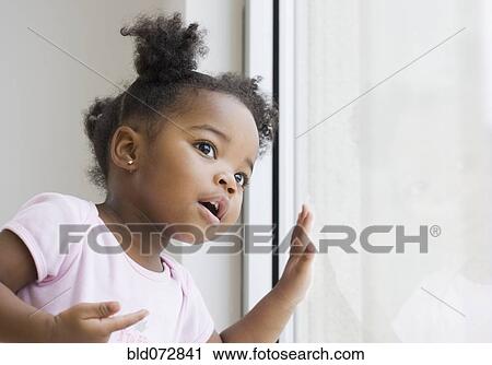 Stock Image - African American girl looking out window. Fotosearch