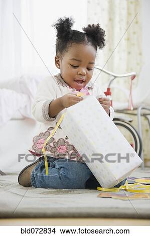 Picture - African American girl opening birthday gift. Fotosearch