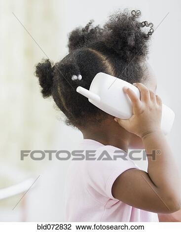 Stock Image - African American girl playing with toy phone. Fotosearch