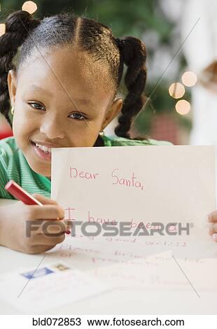 Stock Image - African American girl writing letter to Santa Claus. Fotosearch