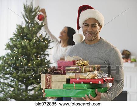 African American man holding Christmas gifts by tree View Large Photo Image Stock Photography - African American man holding Christmas gifts by tree. Fotosearch