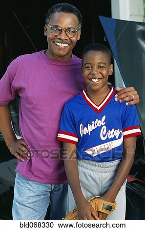 Stock Image - African boy in baseball uniform with father. Fotosearch