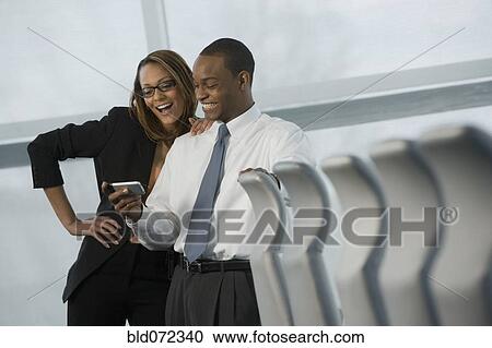 Stock Image - African business people looking at cell phone and smiling. Fotosearch