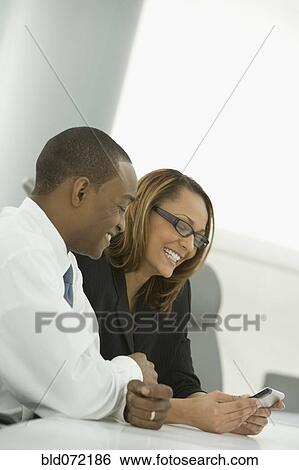 African business people looking at cell phone and smiling View Large Photo Image Stock Photograph - African business people looking at cell phone and smiling. Fotosearch
