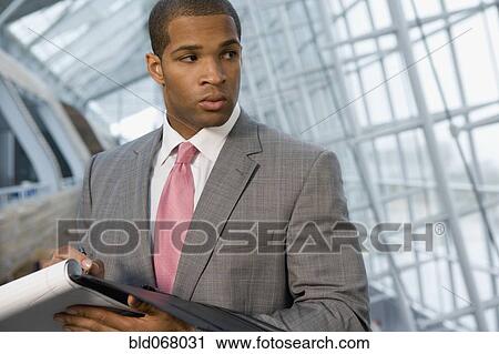 Stock Image - African businessman holding paperwork. Fotosearch