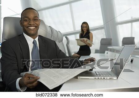 African businessman reading newspaper in conference room View Large Photo Image Stock Photo - African businessman reading newspaper in conference room. Fotosearch