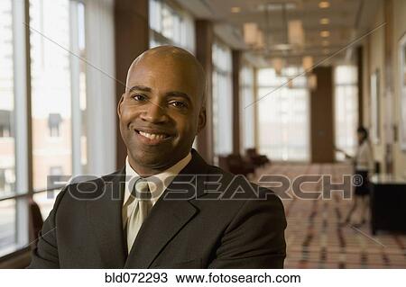 Stock Image - African businessman smiling in hotel corridor. Fotosearch