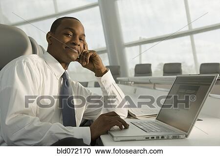 African businessman working on laptop and smiling View Large Photo Image Stock Image - African businessman working on laptop and smiling. Fotosearch