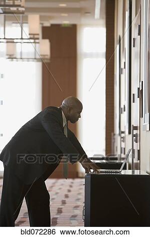 African businessman working on laptop in corridor View Large Photo Image Stock Photograph - African businessman working on laptop in corridor. Fotosearch