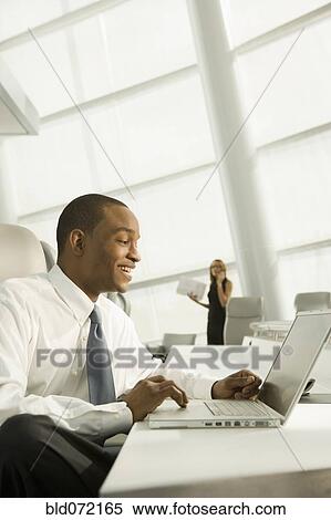 African businessman working on laptop and laughing View Large Photo Image Stock Photography - African businessman working on laptop and laughing. Fotosearch