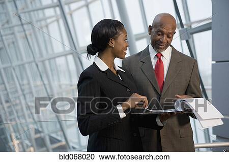 Stock Image - African businesspeople reviewing paperwork. Fotosearch