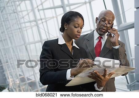 Stock Image - African businesspeople reviewing paperwork. Fotosearch