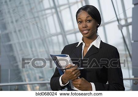 Picture - African businesswoman holding paperwork. Fotosearch