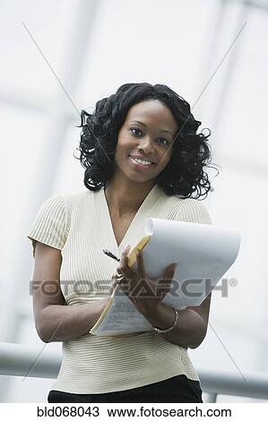 Stock Image - African businesswoman holding paperwork. Fotosearch