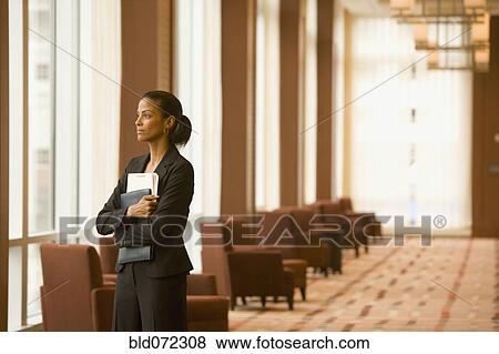 Stock Photo - African businesswoman holding paperwork in hotel lobby. Fotosearch