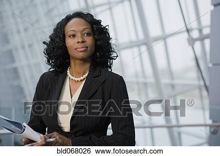 Stock Photograph - African businesswoman holding paperwork. Fotosearch