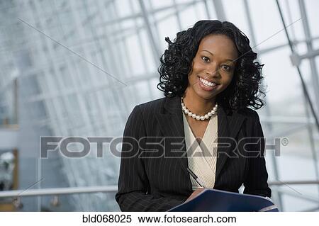Stock Photography - African businesswoman holding paperwork. Fotosearch