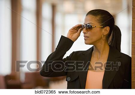 Stock Photography - African businesswoman putting on sunglasses. Fotosearch