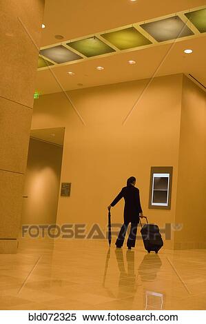African businesswoman walking with suitcase through lobby View Large Photo Image Stock Photography - African businesswoman walking with suitcase through lobby. Fotosearch