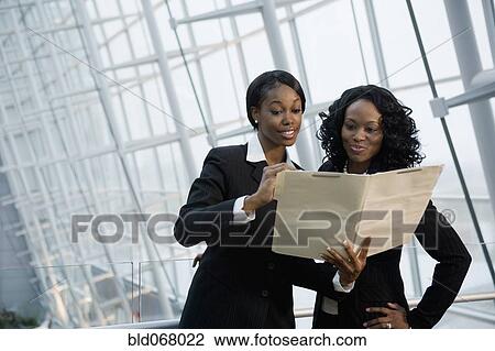 Stock Image - African businesswomen viewing folder. Fotosearch