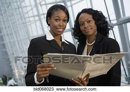 Stock Image - African businesswomen viewing folder. Fotosearch
