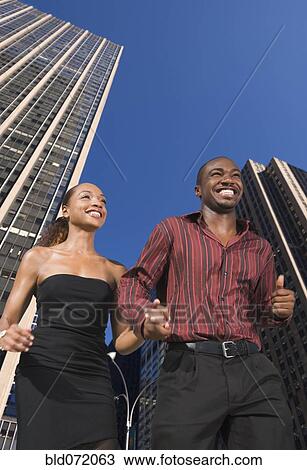 Stock Image - African couple holding hands in urban scene. Fotosearch