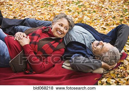 African couple laying on blanket among autumn leaves View Large Photo Image Stock Photo - African couple laying on blanket among autumn leaves. Fotosearch