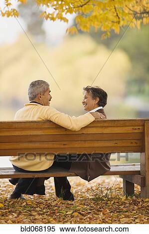 Stock Photography - African couple sitting on park bench in autumn. Fotosearch