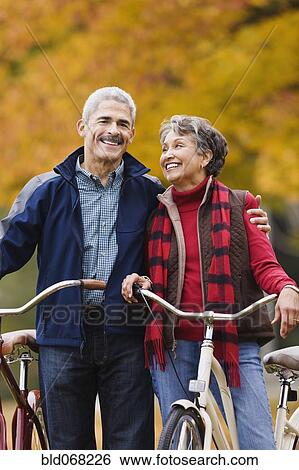 Stock Photograph - African couple standing with bicycles in park in autumn. Fotosearch