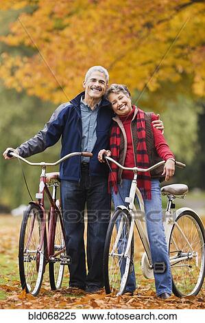 Stock Photography - African couple standing with bicycles in park in autumn. Fotosearch
