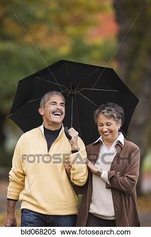 Stock Photography - African couple walking with umbrella in autumn. Fotosearch