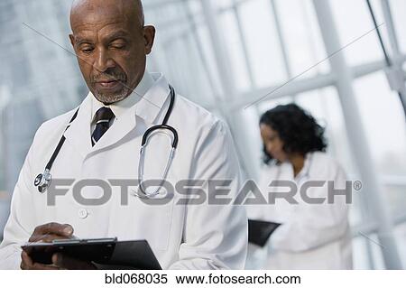 Stock Photography - African doctor reviewing medical chart. Fotosearch