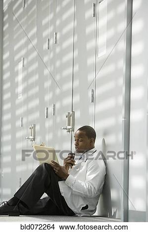African doctor sitting on floor dictating medical record into recorder View Large Photo Image Picture - African doctor sitting on floor dictating medical record into recorder. Fotosearch