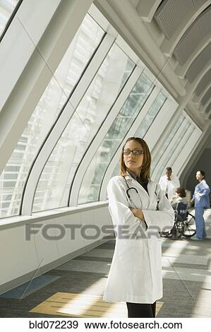 Stock Photo - African doctor with arms crossed looking pensive in corridor. Fotosearch