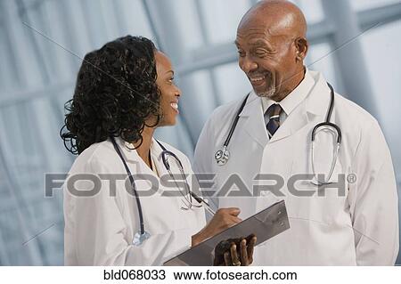 Stock Image - African doctors reviewing medical chart. Fotosearch